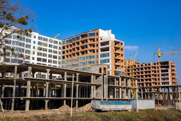 Work in progress on a new apartment block. Tall building under construction with cranes. Construction Site of New Building