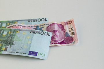 Turkish two hundred liras on white surface with euro and US dollar bills.