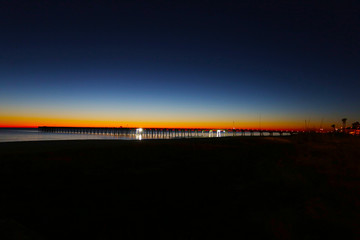 Fototapeta premium Panama city beach florida pier at sun down with beach silhouette and multi colored sky