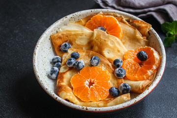 crepes with citrus, jam and berries (thin pancakes, mandarin, blueberry) menu concept. background. top view. copy space for text