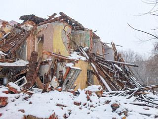 Destroyed old brick house in a snowfall