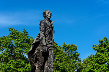 Fototapeta na wymiar Russia, Black Sea, Sochi: Nikolai Ostrovsky statue monument in a public park in the city center of the Russian town with square, green trees, garden and blue blue sky - literature author culture