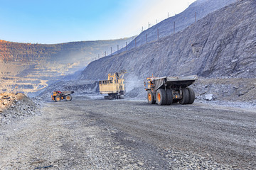 Excavator and two trucks in the iron ore quarry