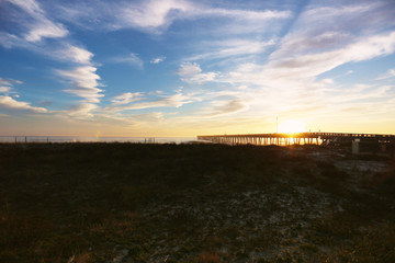 sundown at panama city beach pier with silhouette beach and pier and sunset clouds and sky