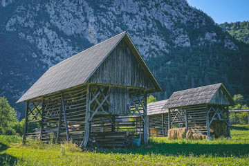 Obraz premium Hay sheds in Slovenian Alps with mountains in the background