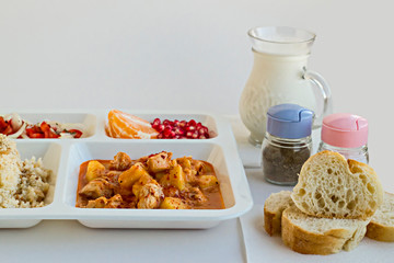 Traditional Turkish Meal with chicken potato,rice,tomato salad and fruits in the white portion food tray.Table d'hote-known TABLDOT in TR-Designed on the white surface.
