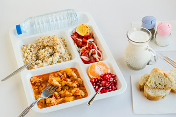 Traditional Turkish Meal with chicken potato,rice,tomato salad and fruits in the white portion food tray.Table d'hote-known TABLDOT in TR-Designed on the white surface.