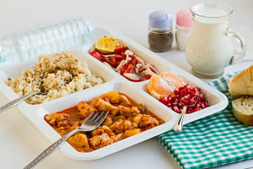 Traditional Turkish Meal with chicken potato,rice,tomato salad and fruits in the white portion food tray.Table d'hote-known TABLDOT in TR-Designed on the white surface.