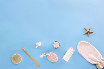 Natural cosmetics, cream, skin tonic, pumice stone, wooden toothbrush, cosmetic mittens and handmade soap on a blue table. Sustainable lifestyle concept. Top view, flat lay, copy space.