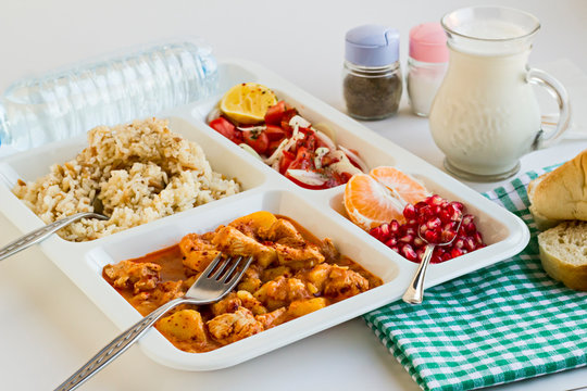 Traditional Turkish Meal with chicken potato,rice,tomato salad and fruits in the white portion food tray.Table d'hote-known TABLDOT in TR-Designed on the white surface.