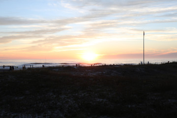beautiful sunset sky sun going down over panama city beach with silhouettes of people
