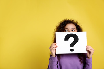 African-American woman with question mark sign on yellow background. Space for text