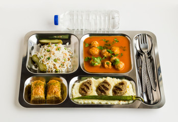 Traditional Turkish meals,meatballs soup,rice,mashed potatoes,grilled meatball and two slices of baklava in stainless steel food tray.Table d'hote(known Tabldot in Turkey) top view.