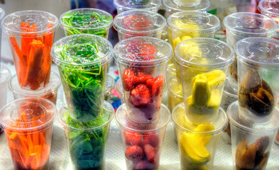 Fresh fruits and vegetables in transparent plastic cups ready to eat at street market in Thailand.