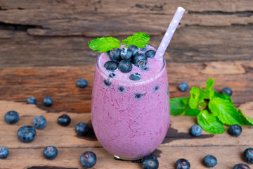 Blueberry smoothie purple colorful fruit juice milkshake blend beverage healthy high protein the taste yummy In glass drink episode morning on wooden background.