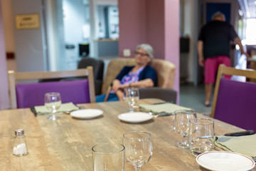 Résidente assise maison de retraite dans le salon avant le déjeuner table servie