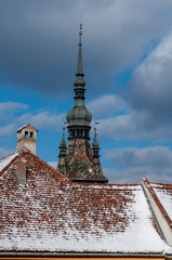 Obraz premium A rooftop and a church steeple. Rooftop covered with snow. Winter scene.