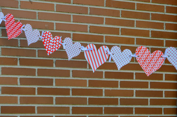 Fototapeta premium garland with paper hearts on brick background
