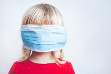 Small Girl with face hidden under surgical mask as virus protection.