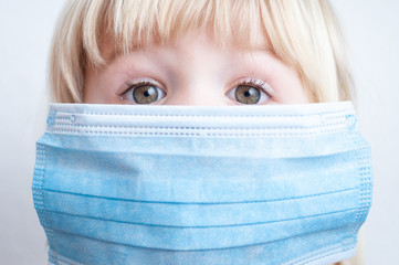 Cute small girl with surgical mask on a face. Prevention against illnes, coronavirus etc.
