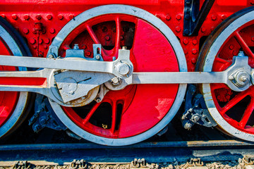 Red driving wheels of a vintage steam engine locomotive. Driving rods, drives, cranks and other parts. The history of railway transport.