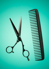 Barber scissors or hairdresser shears and comb. Concept for beauty salon. Scissors for haircut. Blue - green background.