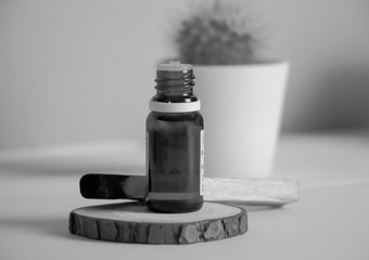 Frasco de aceite esencial destapado sobre tronco con palo santo en blanco y negro
