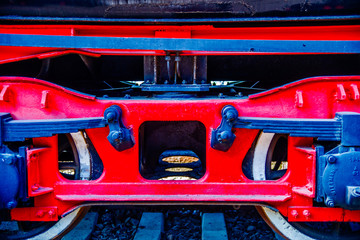 A wheel pair of a vintage railway carriage. Red frame, black plate springs or shock absorbers. The history of railway transport.