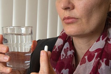 Closeup of woman taking headache tablets