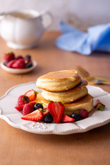Pile of trendy Japanese fluffy pancakes for breakfast with berries white plate