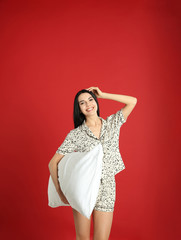 Young woman with pillow on red background