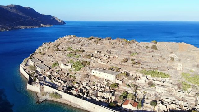 Aerial perspective of Spinalonga fortress, old structures vestiges and ruins on small rocky hill. Former military site and leper colony, famous landmark at North-East shore of Crete Island