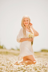 beautiful girl in a delicate dress in a field of daisies