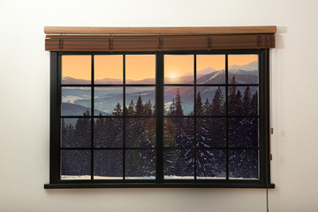 Beautiful view of snowy forest at sunset through big window