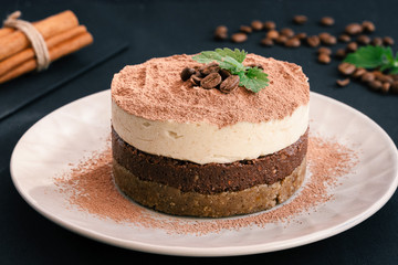 Tiramisu on a beige plate. Coffee with cinnamon. Raw dessert