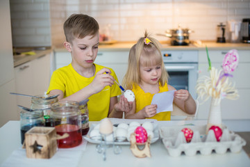 Obraz na płótnie Canvas Kids draw easter eggs in the kitchen