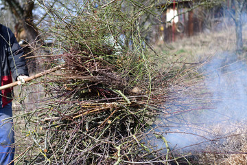 Cleaning the garden from dry leaves and branches in a village in spring