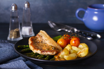 Roast pork chop with pepper sauce, asparagus, potatoes and tomatoes