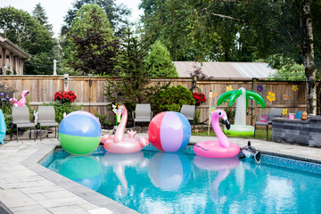 An inviting backyard pool full of hawaiin themed toys.