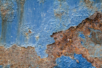 Peeling blue paint on a rusted metal surface