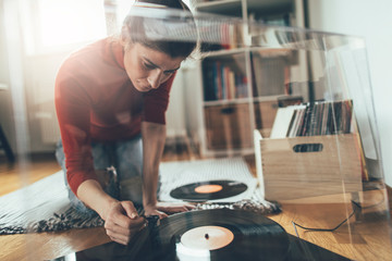 Hipster girl playing vinyl record on turntable