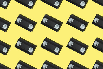 Seamless pattern with retro vhs tapes flat lay on colorful yellow background top view. Creative...