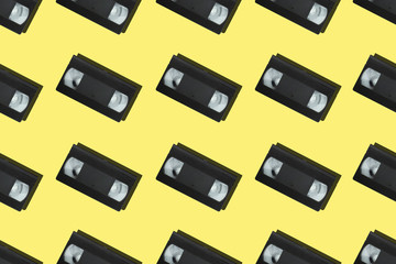 Seamless pattern with retro vhs tapes flat lay on colorful yellow background top view. Creative design in minimal retro 80-s style. Web banner template. Stock photo.