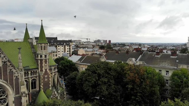 Cityscape of Lviv. Pigeons fly near the old church. Landmarks and architecture of Lviv city. Popular tourist places. Aerial Drone 4K cinematic footage