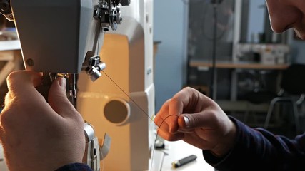 A man sets up an old sewing machine for work. Sewing factory.