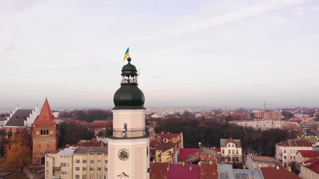 City Hall of Drohobych city with cityscape, smooth pan around tower. Blue and yellow the flag of Ukraine on the spire. Ancient European city of Drohobych. Aerial drone view