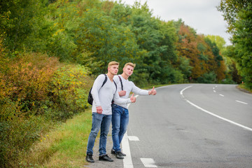 Begin great adventure in your life with hitchhiking. Company friends travelers hitchhiking at road nature background. Go near edge of city. Travellers on their way. Friends hitchhikers travelling