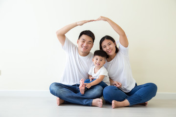 Dad and mom making roof figure home with hands arms over heads, Asian Family with son sitting on floor in the room, New building residential house purchase apartment concept
