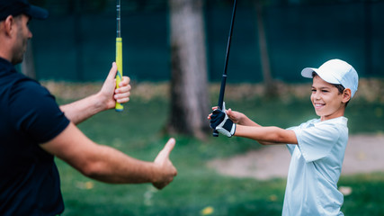 Golf Instructor adjusting young boy’s grip