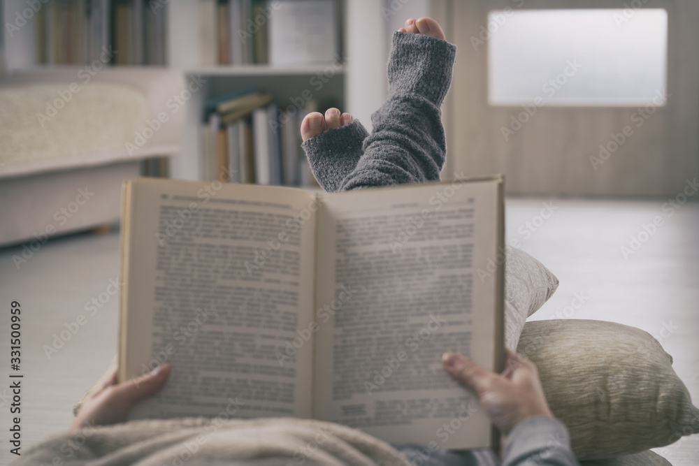 Wall mural woman reading book on sofa